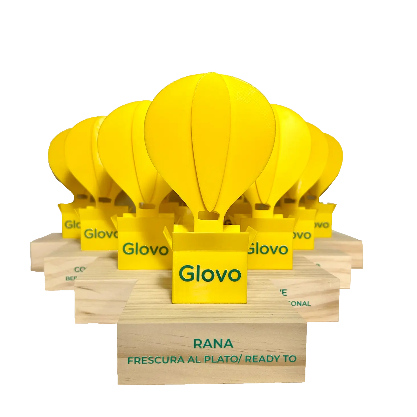 Trofeos amarillos para la empresa de delivery Glovo, sobre bases de madera con nombres de empresas.