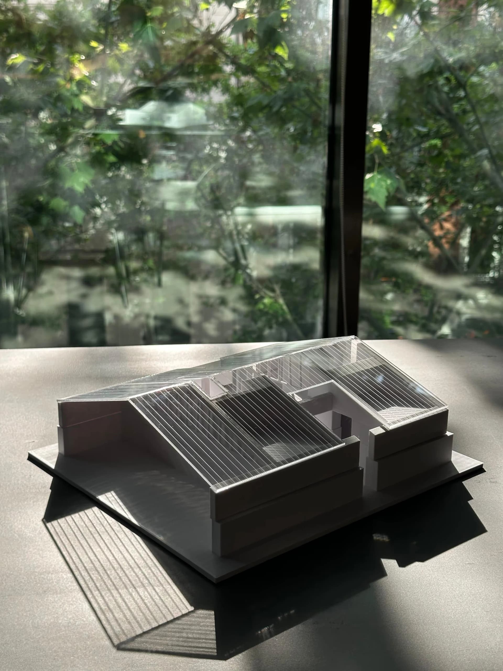 Foto d'una maqueta 3D blanca per a un estudi d'arquitectura; hi ha un fons amb plantes a la foto