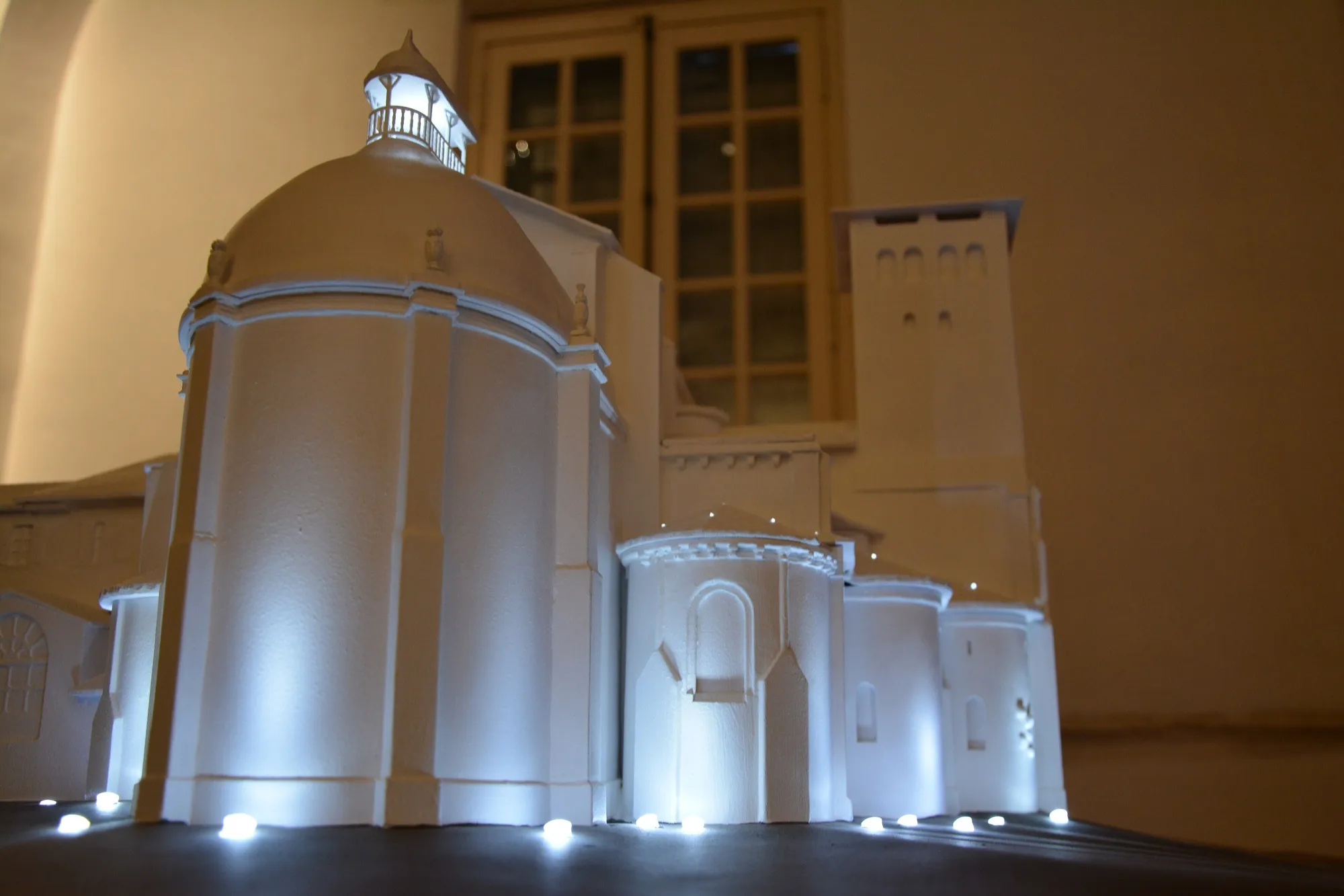 Illuminated scale model of a domed building at night.