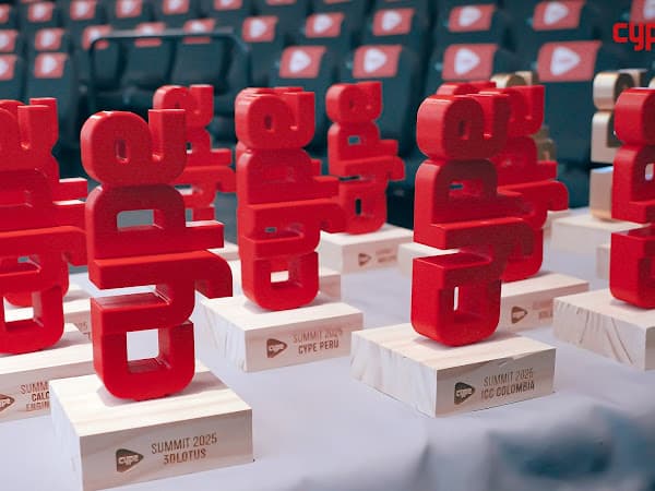 Trofeo gorriak oinarri zuriarekin CYPEren 2025eko Summiterako, mahai baten gainean lerrokatuta.